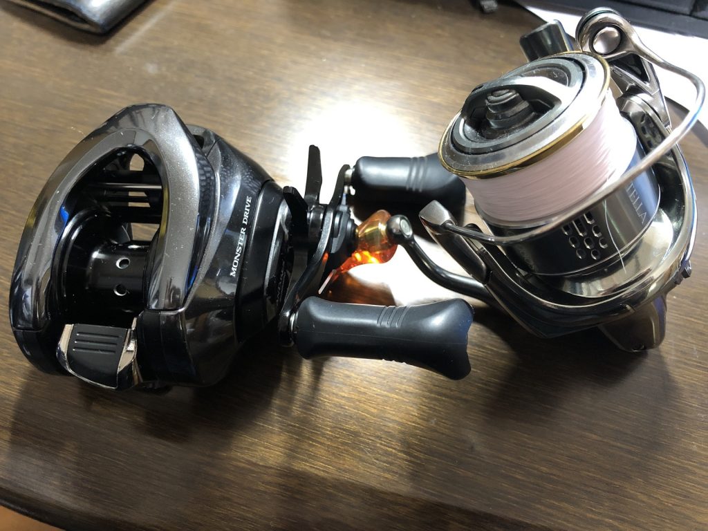 机の上にベイトリールとスピニングリールを置いた画像